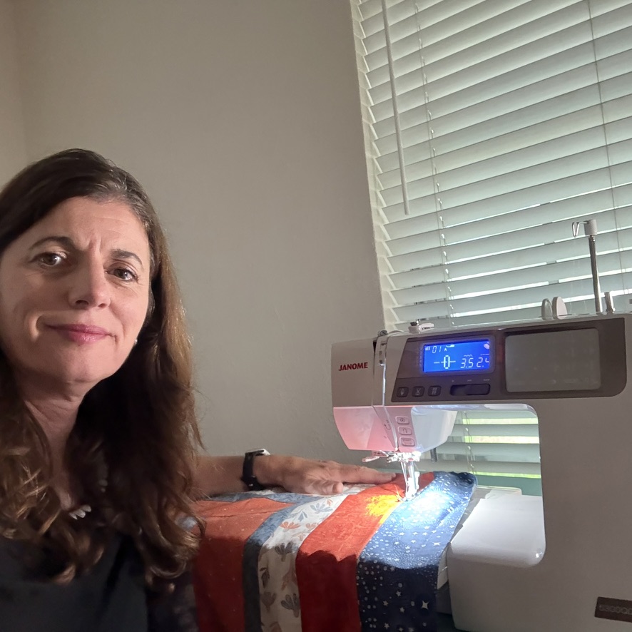 Katie at her sewing machine with a quilt under the needle